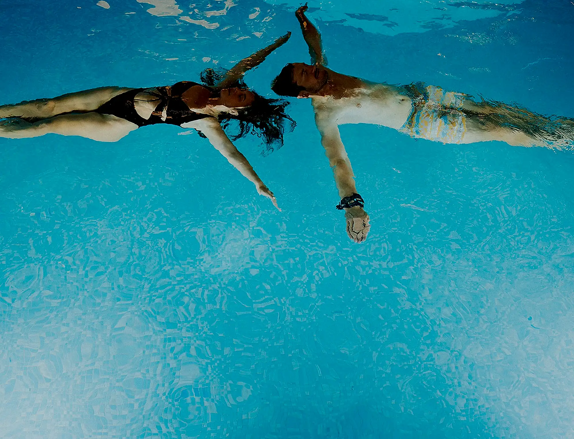 A man and a woman swimming next to each other in a swimming pool