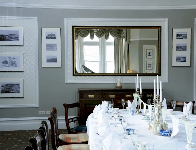 An elegant, traditional function room at a luxury Newquay hotel, featuring a grand banquet table dressed in crisp white linen, sophisticated place settings, and flickering candles