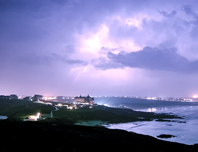 Purple stormy sky overlooking Newquay, Cornwall’s coastline, with The Headland Hotel on the cliff-top.