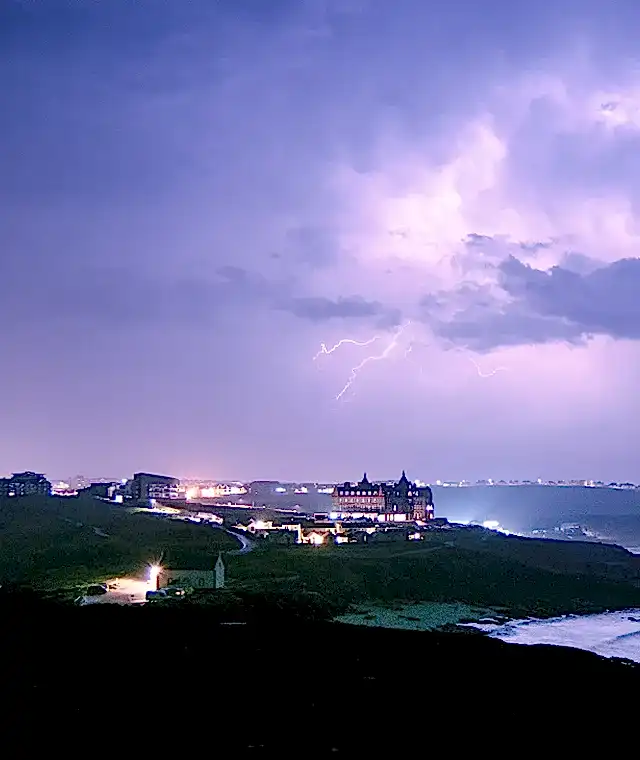 Purple stormy sky overlooking Newquay, Cornwall’s coastline, with The Headland Hotel on the cliff-top.