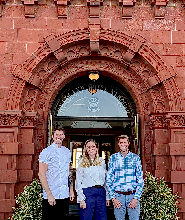 Three people standing outside the entrance to the Headland Hotel
