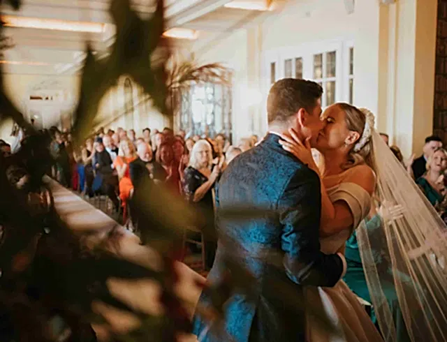 A bride and a groom kissing in front of a congregation
