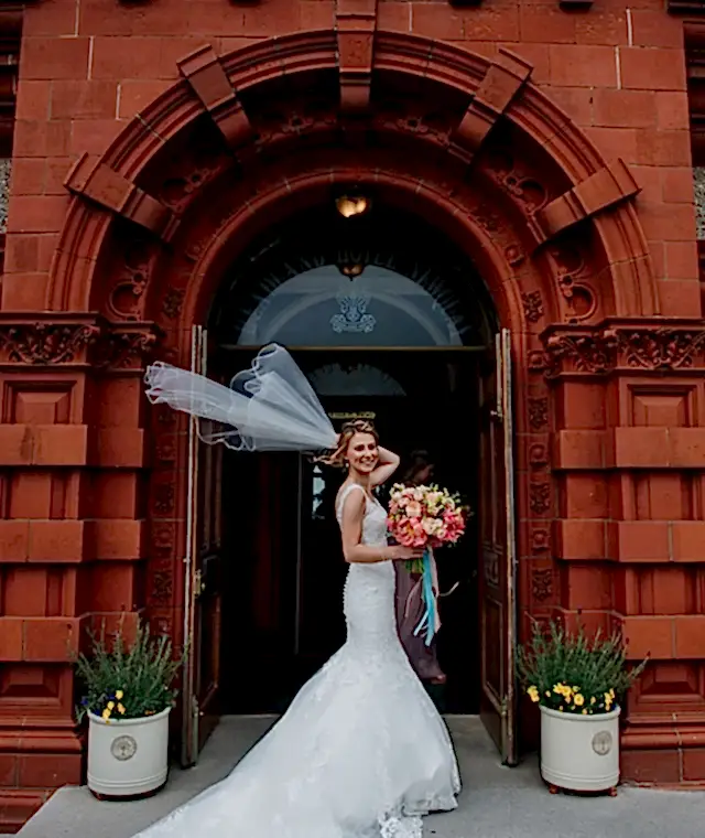 A bride holding a bouquet standing outside the entrance of the Headland Hotel