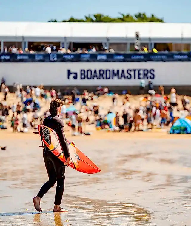 A surfer on a crowded beach during Boardmasters Festival