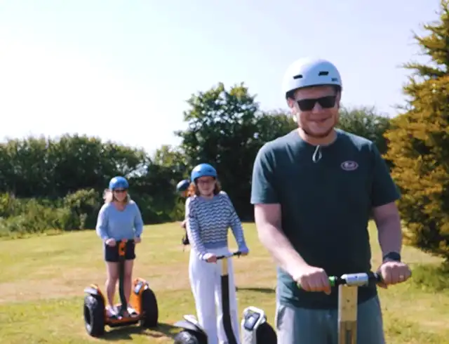 Three people riding segways on the grass