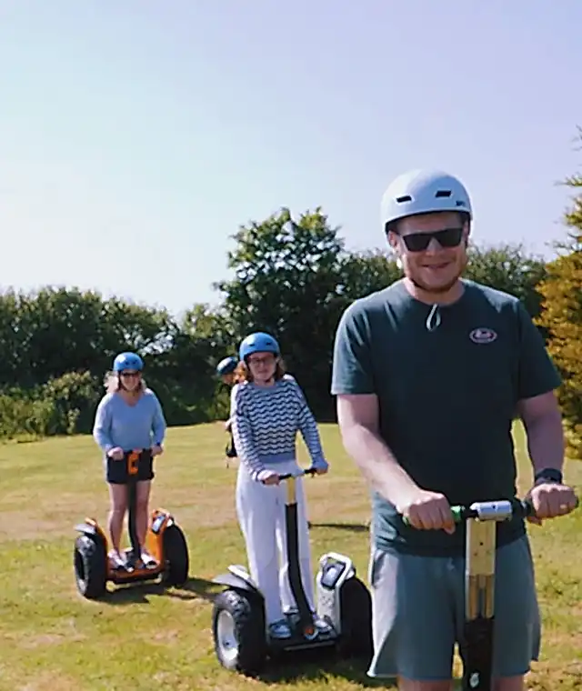Three people riding segways on the grass