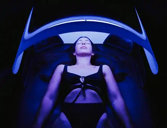 High-contrast image of a woman lying down in a swimming costume on a modern technology massage bed.