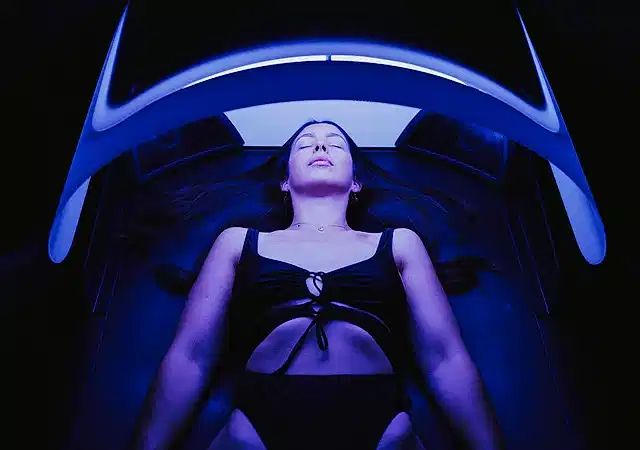 High-contrast image of a woman lying down in a swimming costume on a modern technology massage bed.