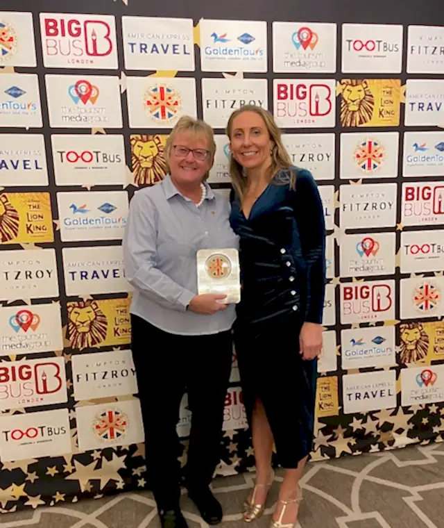 Two ladies standing with an award