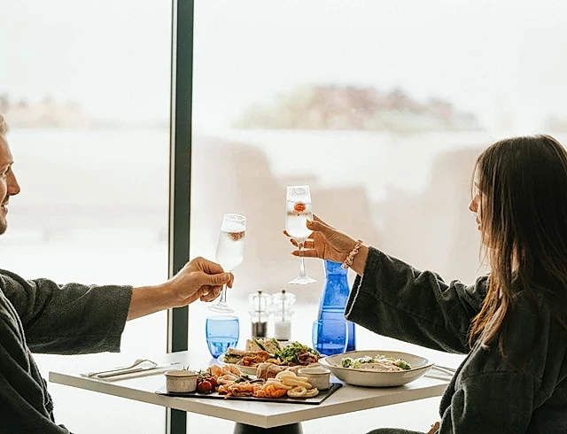 a couple toasting over a meal in a restaurant