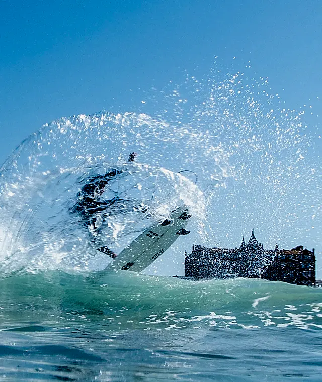 a surfer splashing in the waves outside the Headland Hotel