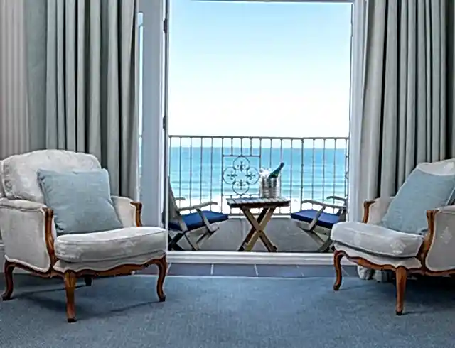 Two chairs overlooking the beach next to a window