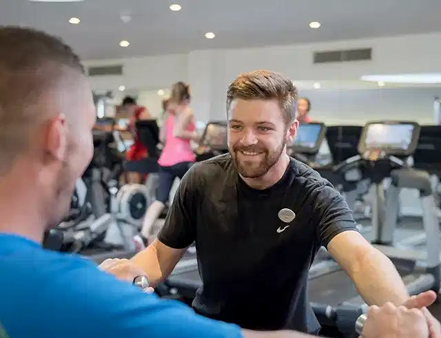 A personal trainer supervising a man on a treadmill
