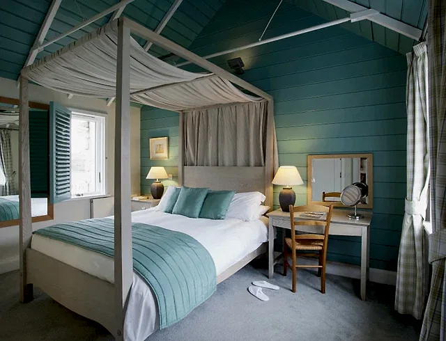 A sky blue four poster bed in a luxury room