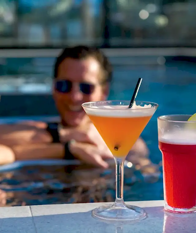Two ladies enjoying two cocktails sitting in a swimming pool