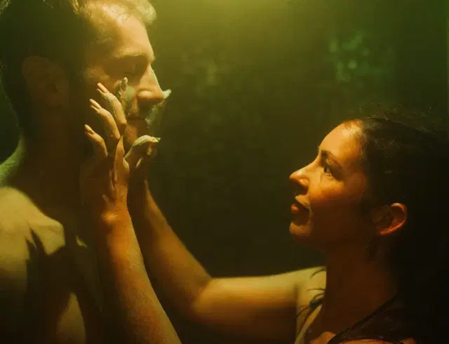 a woman applying a mud mask to a man's face