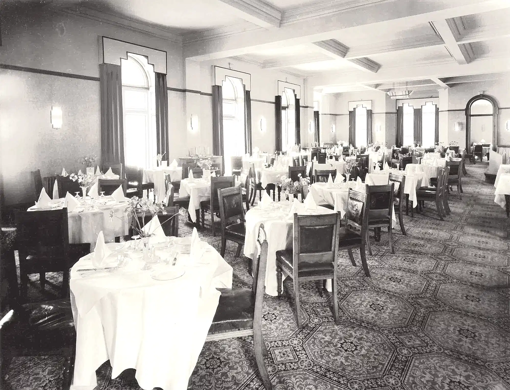 Vintage black-and-white interior of The Headland Hotel ballroom featuring formal table settings and 20th-century architectural details.