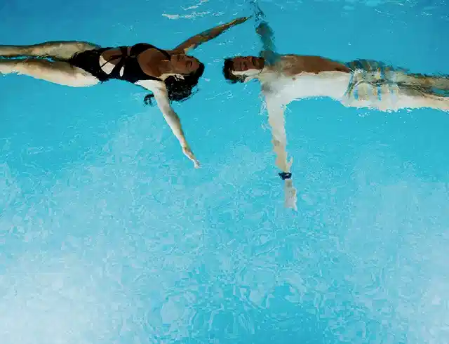 A man and a woman swimming next to each other in a swimming pool
