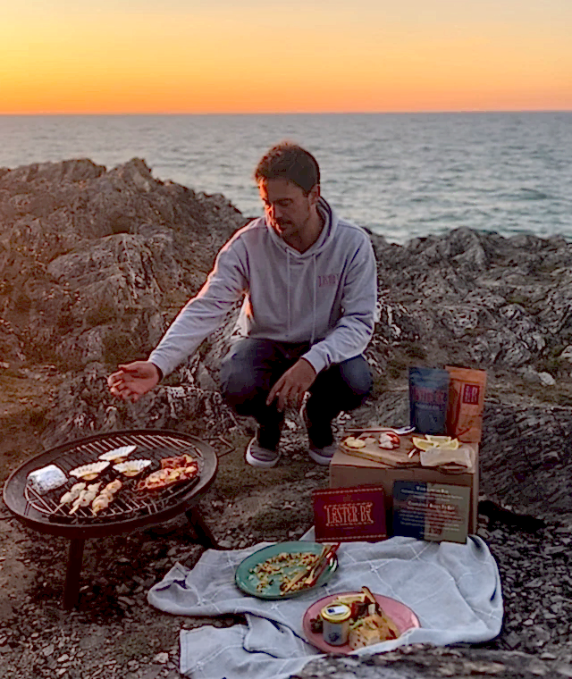 A man enjoying a seafood platter on a rock