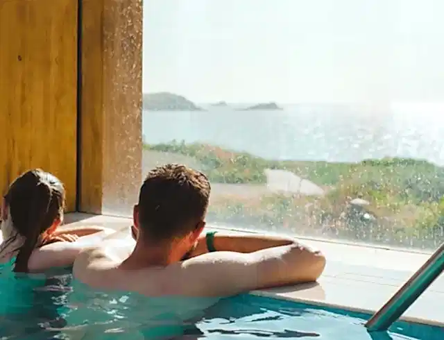 Two people in the swimming pool looking out of the window of the Headland Hotel