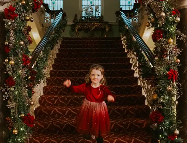 A child walking down the staircase with Christmas decorations
