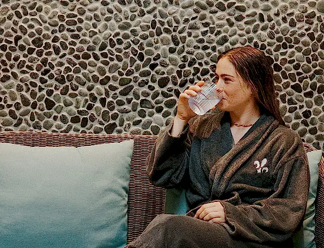 a girl sipping on a drink sat on a sofa