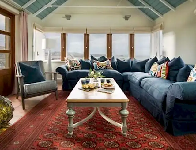 A view of the beach in the background in a room with an L shaped sofa