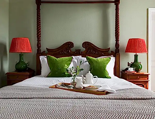 A breakfast tray sitting atop a four poster bed in a luxury bedroom