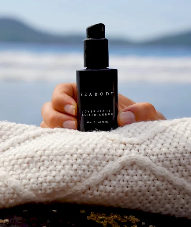 A hand holding a bottle of fragrance
