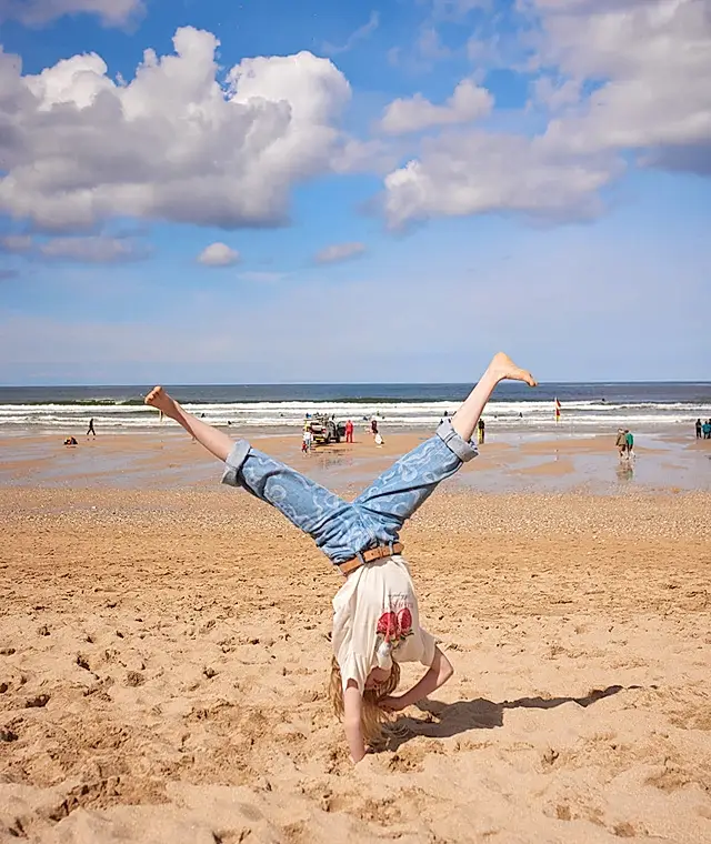 A girl doing a handstand on a beach
