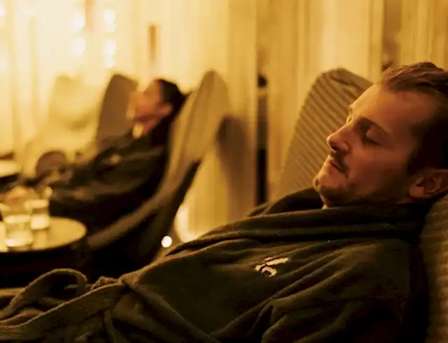 two people relaxing in a lounge in the foreground with others in the background