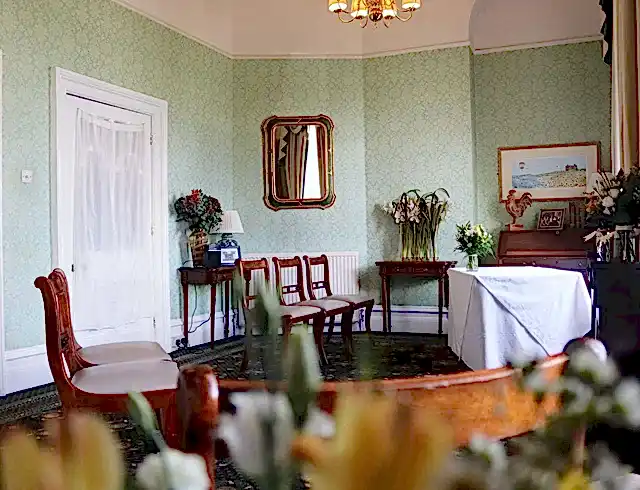 Image of a traditional-style conference room, decorated with bouquets of yellow and green flowers along with wooden furniture and framed artwork. 