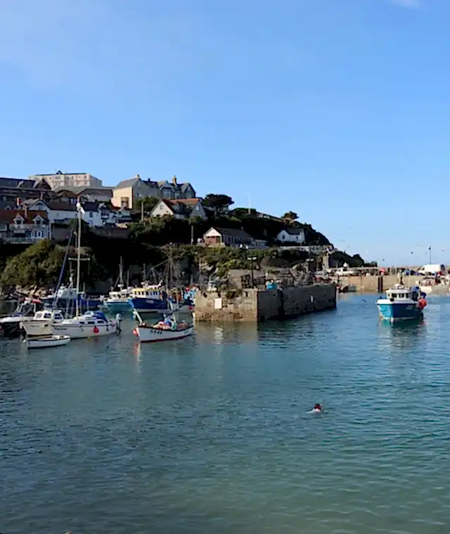 A view of a Cornish harbour with a boat sailing through it