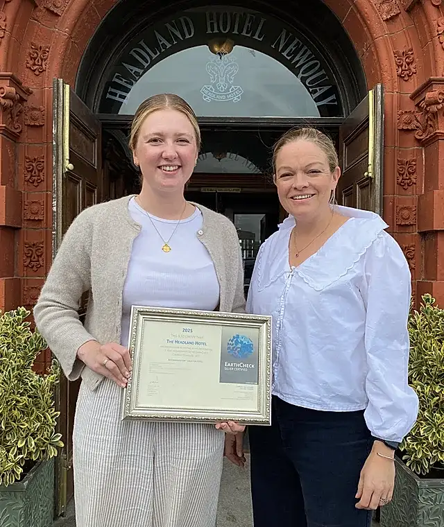 Two ladies holding up the Earthcheck certification